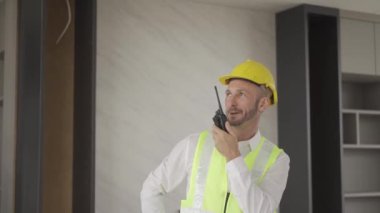 Engineers use walkie-talkies to communicate with crews while working in a factory. Foreman gives work instructions, talks using a walkie-talkie, works at a construction site.