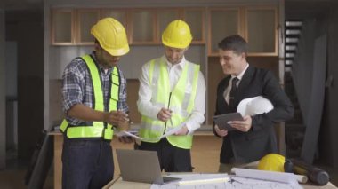 Architect discussing blueprints on laptop with construction manager Engineer talking to contractor consultant on construction site about construction project and business workflow in new building