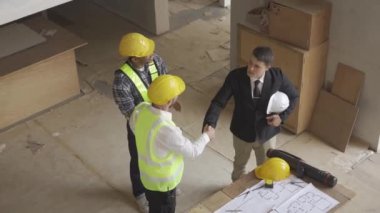 Architect discussing blueprints on laptop with construction manager Engineer talking to contractor consultant on construction site about construction project and business workflow in new building