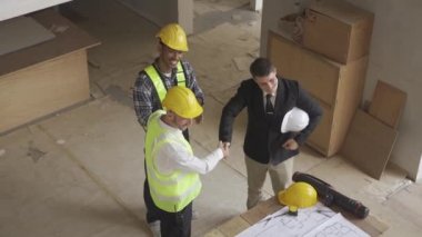 Architect discussing blueprints on laptop with construction manager Engineer talking to contractor consultant on construction site about construction project and business workflow in new building