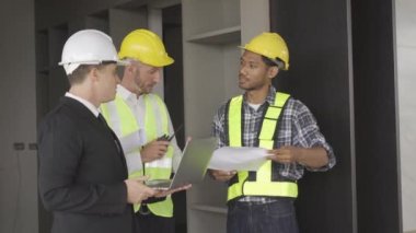 Architect discussing blueprints on laptop with construction manager Engineer talking to contractor consultant on construction site about construction project and business workflow in new building