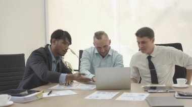Three businessmen having a business meeting negotiating in reaching an agreement Discussing projects, working as a team, sharing ideas in company office with laptop and graph papers on table