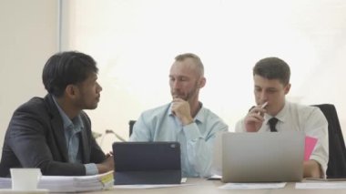 Three businessmen having a business meeting negotiating in reaching an agreement Discussing projects, working as a team, sharing ideas in company office with laptop and graph papers on table