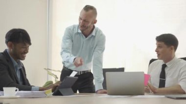 Three businessmen having a business meeting negotiating in reaching an agreement Discussing projects, working as a team, sharing ideas in company office with laptop and graph papers on table