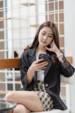 Beautiful Asian woman using smart phone to surf social media, surf the net, chat with friends and play online games. online shopping load the application on the internet