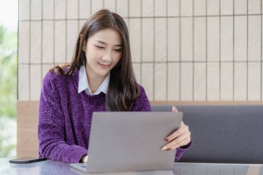 Asian woman working with laptop computer, surfing internet, online shopping, video calling, making friends in free time.