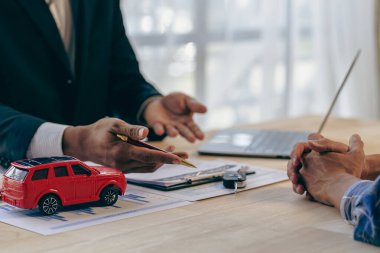 Salesman offers prices and interest rates on car sales with insurance in the office at the desk.