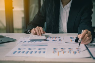 Asian ying businessman hand holding pen pointing at document. Financial graph. Plan. Marketing graph. Finance investment report and business strategy and working on laptop in office.