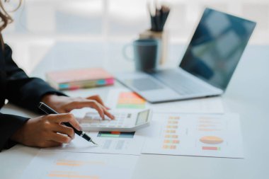 Asian ying businessman hand holding pen pointing at document. Financial graph. Plan. Marketing graph. Finance investment report and business strategy and working on laptop in office.