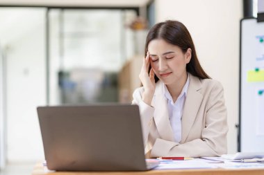 Female accountant having headache with overloaded work Stressed woman with headache working with laptop in office