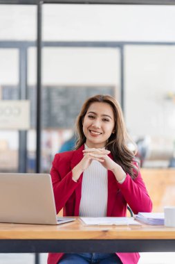 Asian female entrepreneur sitting at table with business documents of accounting firm, auditor, freelancer, finance and investment. Calculation of taxes and budget for each year vertical image
