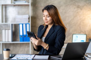 Asian female entrepreneur who uses a calculator to do calculations. Business performance documents of accounting firms, auditors, freelance, finance and investment Tax calculation and budget each year