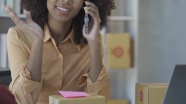 İnternette kıyafet satan üç akıllı telefon kullanan, sipariş alan ve paket gönderen, paketleme siparişlerini müşterilere gönderen genç bir kadın. İnternetten sat. Ticaret 4k.