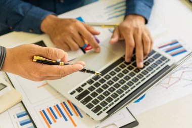 Profesyonel iş ortaklarından oluşan bir ekip elinde kalem tutarak mali grafik belgesini işaret ediyor, analiz ve strateji danışmanlığını hesaplıyor. Toplantı, ofiste beyin fırtınası, takım çalışması konsepti..