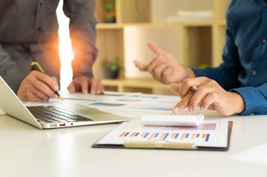 Profesyonel iş ortaklarından oluşan bir ekip elinde kalem tutarak mali grafik belgesini işaret ediyor, analiz ve strateji danışmanlığını hesaplıyor. Toplantı, ofiste beyin fırtınası, takım çalışması konsepti..