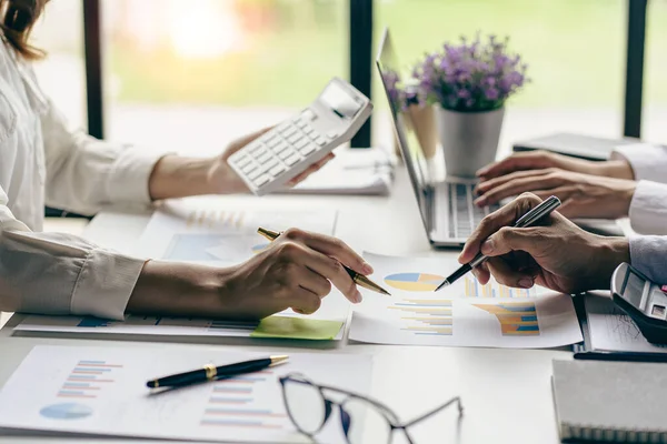 Profesyonel iş ortaklarından oluşan bir ekip elinde kalem tutarak mali grafik belgesini işaret ediyor, analiz ve strateji danışmanlığını hesaplıyor. Toplantı, ofiste beyin fırtınası, takım çalışması konsepti..