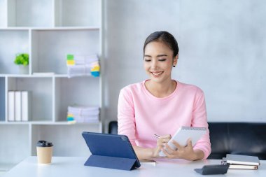 Evde tablet ve defterle çalışan Asyalı kız, online iş konsepti