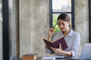 Asyalı iş kadını internet üzerinden ev ofisinden dizüstü bilgisayarla çalışıyor. Postaları kontrol ediyor ya da dairesinde yerde oturmuş telekomünikasyon yaparken bilgi arıyor.