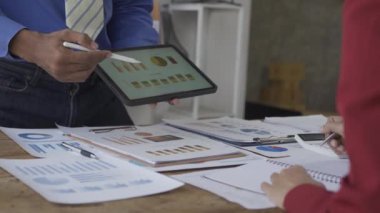 Erkek ve kadın iş adamları mali veri ve grafik tableti ile çalışmayı analiz etmeyi, büyüme, pazarlama ve şirket karına yönelik plan stratejisi hakkında rapor vermeyi tartışıyor. 4k VDO