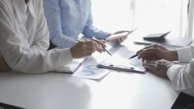 İstatistiksel analiz planlama toplantısında beyin fırtınası yapan Asyalı işadamı ve takım lideri grafikleri gösteriyor ve mali başarı istatistikleri hakkında notlar alıyor. 4k 30p video.