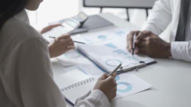 İstatistiksel analiz planlama toplantısında beyin fırtınası yapan Asyalı işadamı ve takım lideri grafikleri gösteriyor ve mali başarı istatistikleri hakkında notlar alıyor. 4k 30p video.