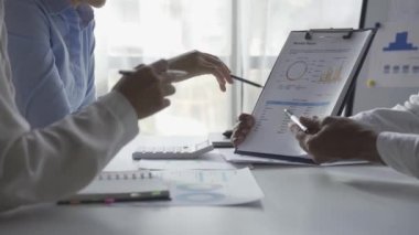 İstatistiksel analiz planlama toplantısında beyin fırtınası yapan Asyalı işadamı ve takım lideri grafikleri gösteriyor ve mali başarı istatistikleri hakkında notlar alıyor. 4k 30p video.