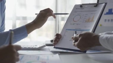 İstatistiksel analiz planlama toplantısında beyin fırtınası yapan Asyalı işadamı ve takım lideri grafikleri gösteriyor ve mali başarı istatistikleri hakkında notlar alıyor. 4k 30p video.