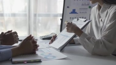 İstatistiksel analiz planlama toplantısında beyin fırtınası yapan Asyalı işadamı ve takım lideri grafikleri gösteriyor ve mali başarı istatistikleri hakkında notlar alıyor. 4k 30p video.