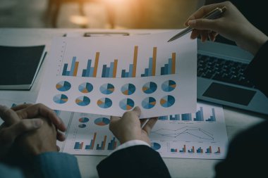 Mali veri analizi ve pazarlama stratejisi projelerini görüşmek üzere iş ekibi toplantısı. Ofiste mali grafik belgeleriyle sunum, yakın plan fotoğraf