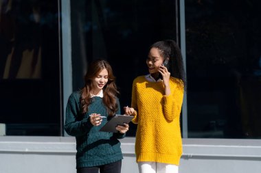 Dışarıdaki ofisin önünde duran iki kadın tablet bilgisayarla konuşuyorlardı. Genç bir kadın ofis dışında arkadaşlarıyla iş konuşuyordu.