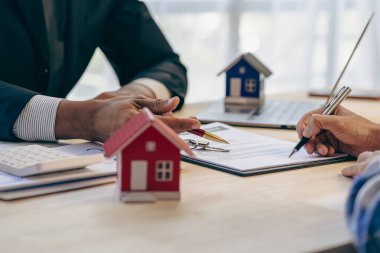 Emlakçılar konut satın almak ya da kiralamak için sözleşme teklif ediyorlar. Küçük bir bina modeline dokunan bir işadamı ve emlak sigortası resimleri kapatır