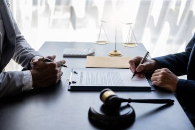 Müvekkille birlikte çalışan avukat, müvekkillerin davaları kazanmasına yardımcı olmak için mahkeme salonundaki hukuk danışmanlığında yüksek dereceli sözleşme belgelerini tartışıyor..