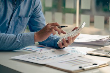 Muhasebeci, aylık mali rapor ya da şirket karını hesaplamak ve gelir, vergi ve giderleri hesaplamak için hesap makinesine baskı yapıyor. Fatura. Çalışan maaşları için kredi kartı.