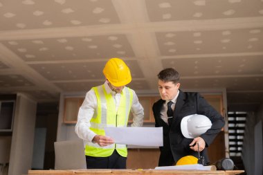 İnşaat ve yapısal konsept mühendisleri, emlak konsepti inşaatında kullanılan modelleme ve mühendislik araçları üzerinde ortaklarla birlikte çalışan projelerin planlama toplantısında çizimler üzerinde çalışıyorlar.