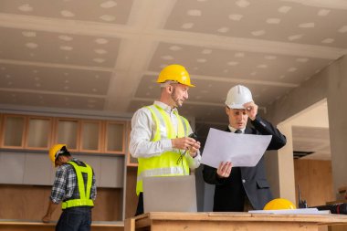 İnşaat ve yapısal konsept mühendisleri, emlak konsepti inşaatında kullanılan modelleme ve mühendislik araçları üzerinde ortaklarla birlikte çalışan projelerin planlama toplantısında çizimler üzerinde çalışıyorlar.