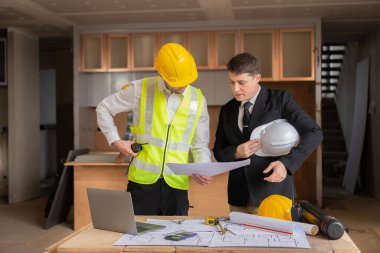 İnşaat ve yapısal konsept mühendisleri, emlak konsepti inşaatında kullanılan modelleme ve mühendislik araçları üzerinde ortaklarla birlikte çalışan projelerin planlama toplantısında çizimler üzerinde çalışıyorlar.