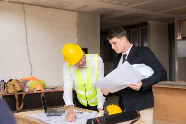 İnşaat ve yapısal konsept mühendisleri, emlak konsepti inşaatında kullanılan modelleme ve mühendislik araçları üzerinde ortaklarla birlikte çalışan projelerin planlama toplantısında çizimler üzerinde çalışıyorlar.