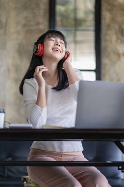 Kulaklık takan genç Asyalı bir öğrenci internette çalışırken en sevdiği şarkıyı dinleyen mutlu bir kadın. Öğrenciler bir dil öğrenmek için sabırsızlanıyor..