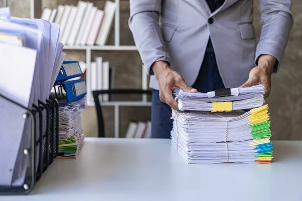 stock image Asian office worker sitting at his desk clearing a lot of papers on the table at the office, OT concept