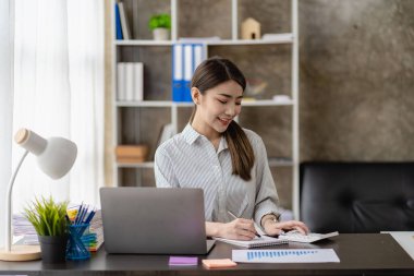 Şirket maliyesini, gelirini ve bütçesini kontrol etmek, aylık giderleri hesaplamak, bütçeyi, belgeyi, krediyi, faturayı yönetmek için hesap makinesi ve dizüstü bilgisayar kullanan iş kadını