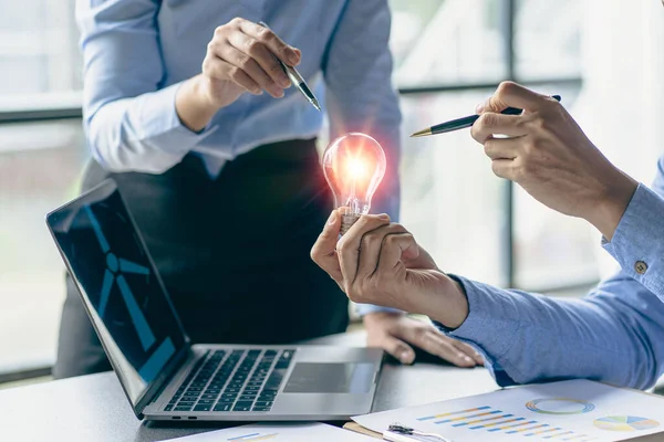 Hand holding a light bulb. Innovation and inspirational concept, businessman holding light bulb hand with financial documents and new concept tools for business and finance.