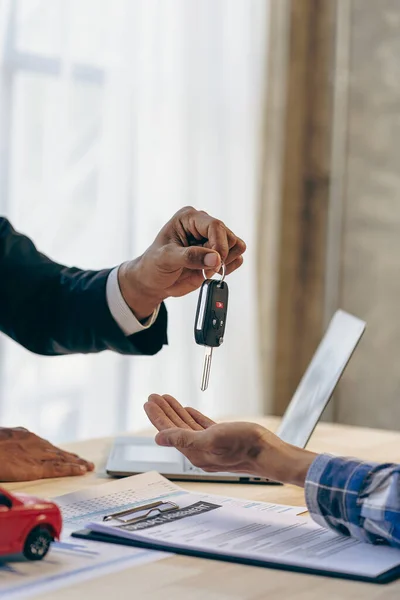 stock image Explain promotions and car insurance for rental or purchase. A car dealer or sales manager hands the keys to the car owner and explains the terms of the car contract at a desk in the office.