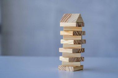 Kule ahşap blok, gri arka plandaki tahta bloklardan kule inşa eder. Ticari düşünce ve risk insanlar gruptan ahşap bloklar çeker.