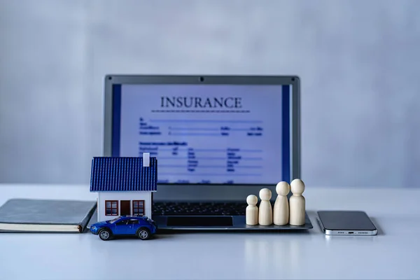Car house, wooden dummy, laptop on table, white background, insurance concept.
