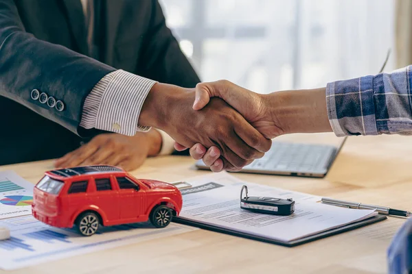 Car business, car dealer presenting car to new owner and shaking hands during congratulating two customers