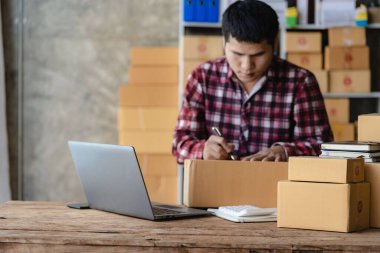 Asyalı Erkek KOBİ Küçük İş Girişimcisi, ticari denetim için dizüstü bilgisayar kullanarak evden çalışıyor. Çevrimiçi pazarlama Paketleme KOBİ Satıcısı Takımının Online satış kavramları