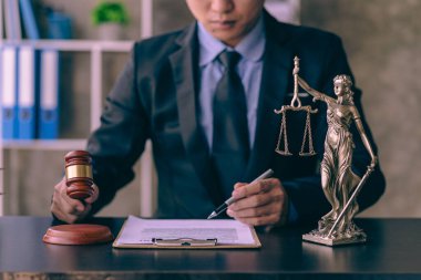 Asyalı genç avukat dizüstü bilgisayar ve çekiçle çalışıyor. İnternetten hukuki tavsiyeler veriyor. Sözleşme kurallarını hukuk danışmanına ve adalet bakanlığına anlatıyor.