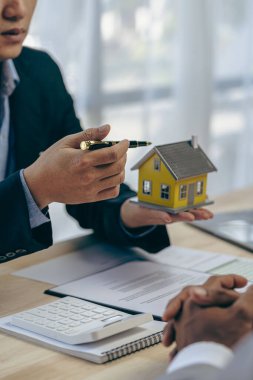 Asyalı erkek emlak işadamı müşterilerine faiz oranları ve sigortası olan evler sunuyor.