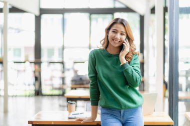Ciddi Asyalı iş kadını müşteri hizmetlerini kullanarak masada oturuyor, satış müdürü ofisteki müşteriyle iş görüşmesi yapan bir kadına odaklanmış durumda.