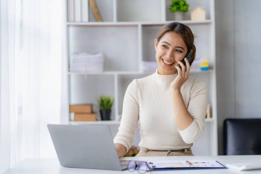 Ciddi Asyalı iş kadını müşteri hizmetlerini kullanarak masada oturuyor, satış müdürü ofisteki müşteriyle iş görüşmesi yapan bir kadına odaklanmış durumda.